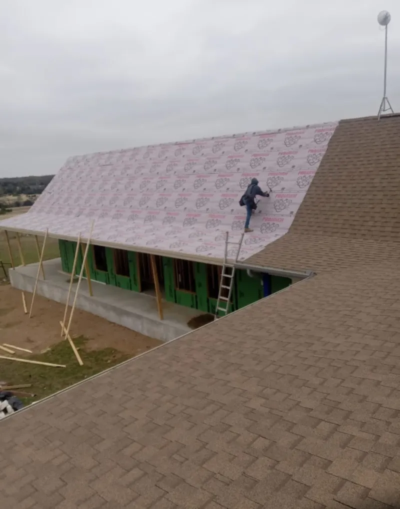 Worker preparing underlayment for a metal roof installation in Kalispell